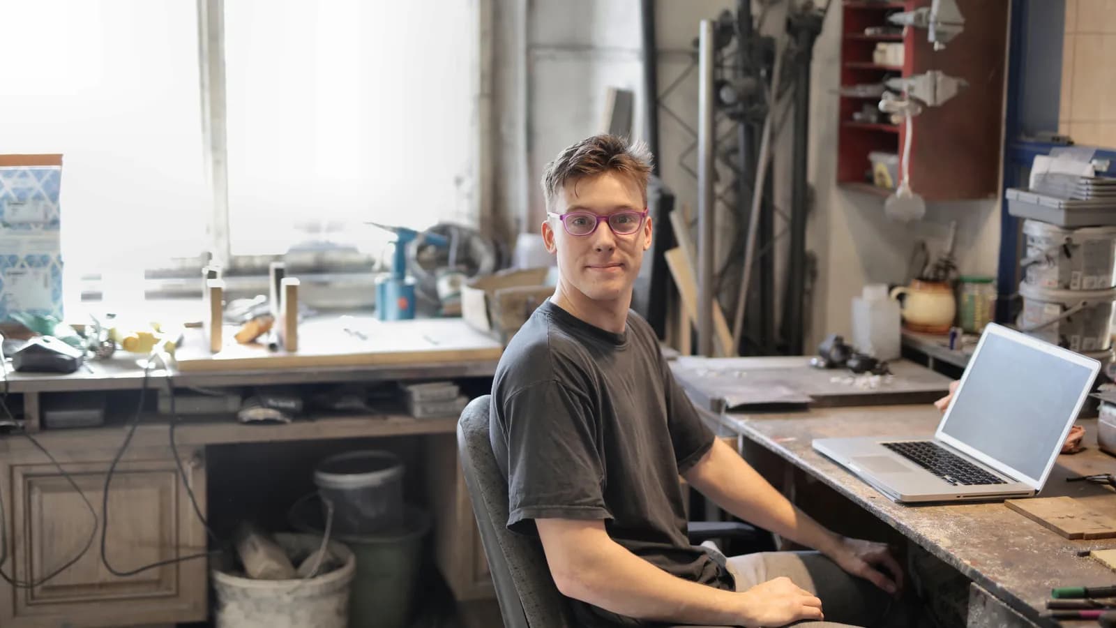 Un jeune artisan assis dans son atelier devant un ordinateur portable