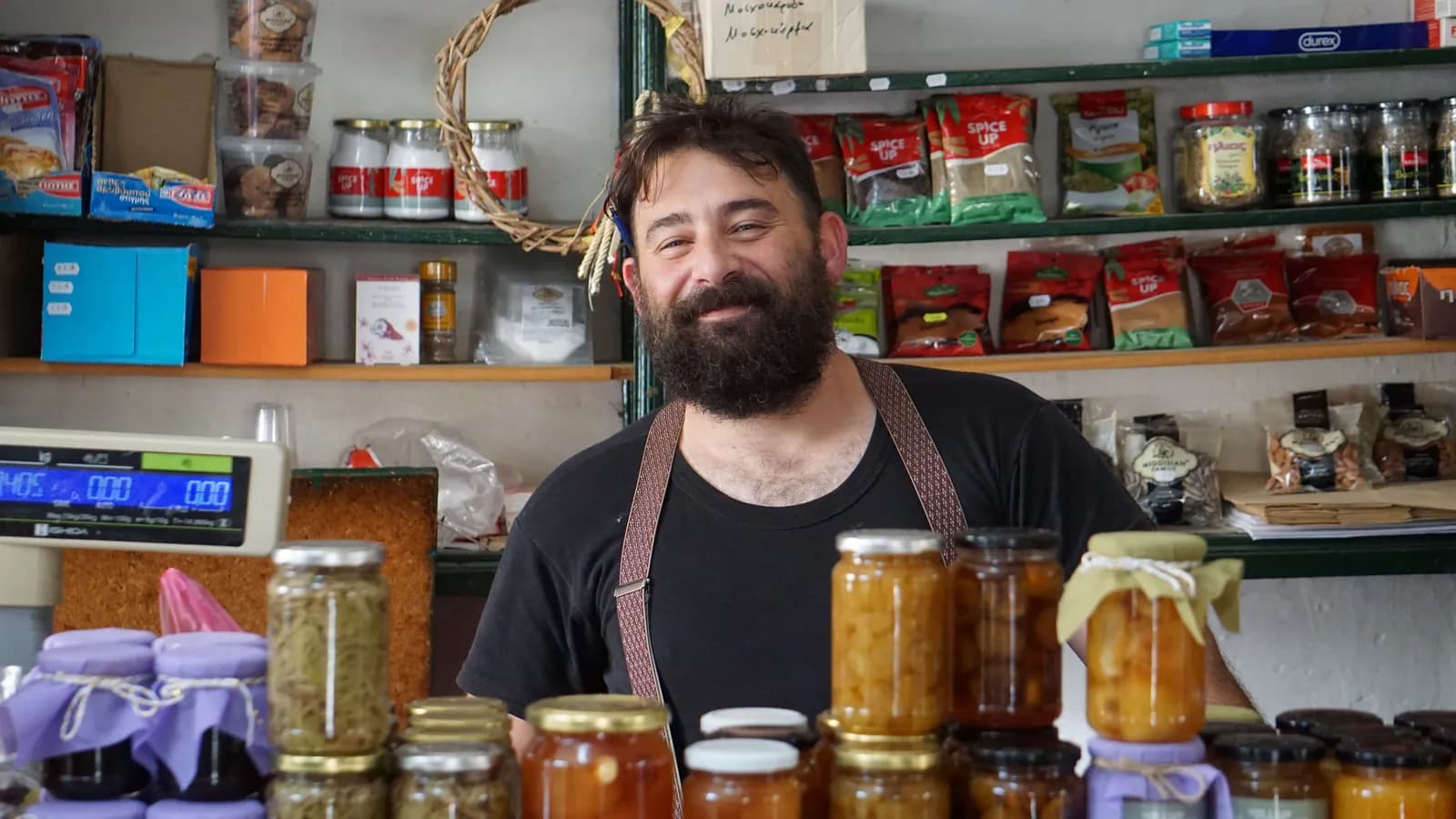 Un commerçant souriant derrière le comptoir de sa petite épicerie