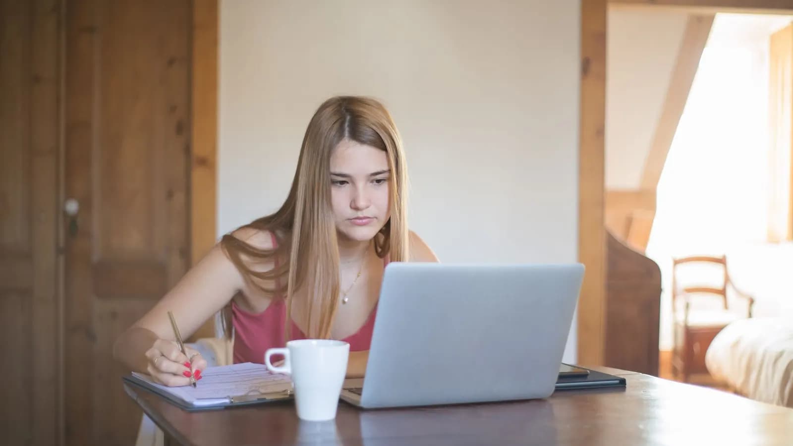 Une professionnelle prend des notes devant son ordinateur portable, en train d'apprendre