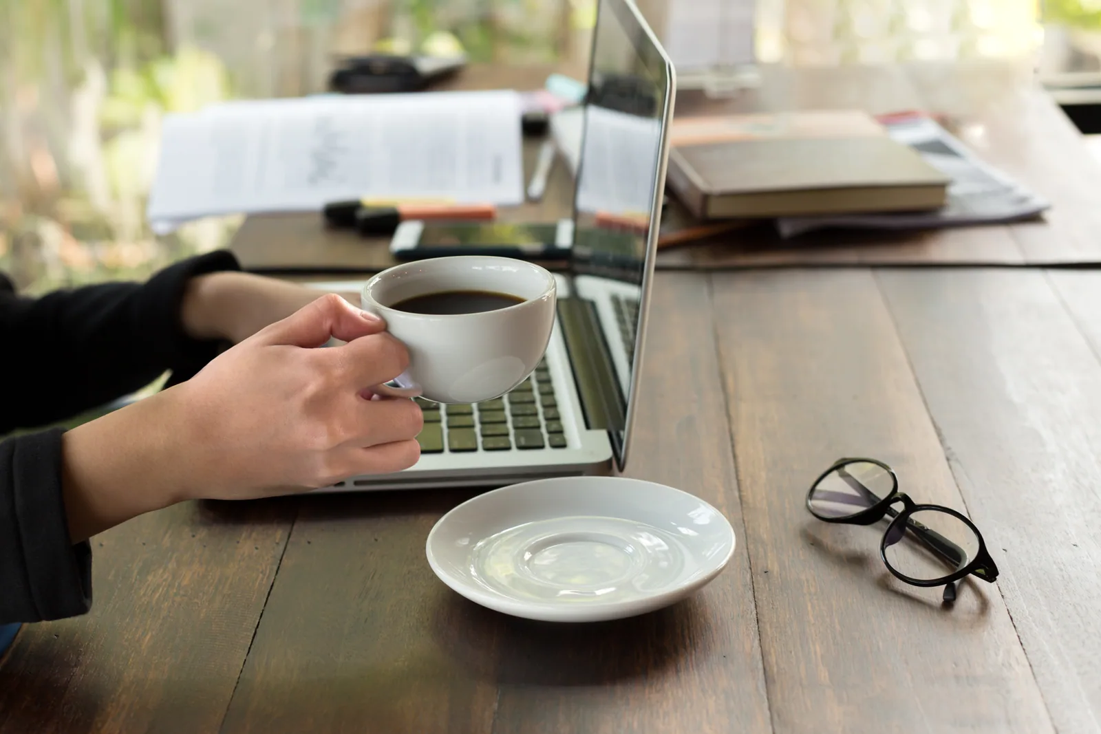 Bureau rangé d'un freelance qui démarre son activité, ordinateur portable ouvert sur une feuille de calcul, mug, agenda