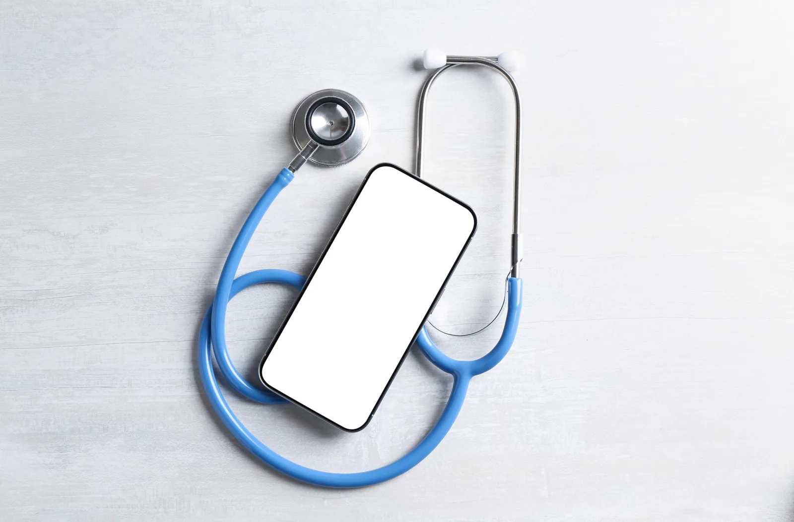 Smartphone et stéthoscope sur table claire, symbole de la convergence entre outils numériques et pratique médicale en 2026