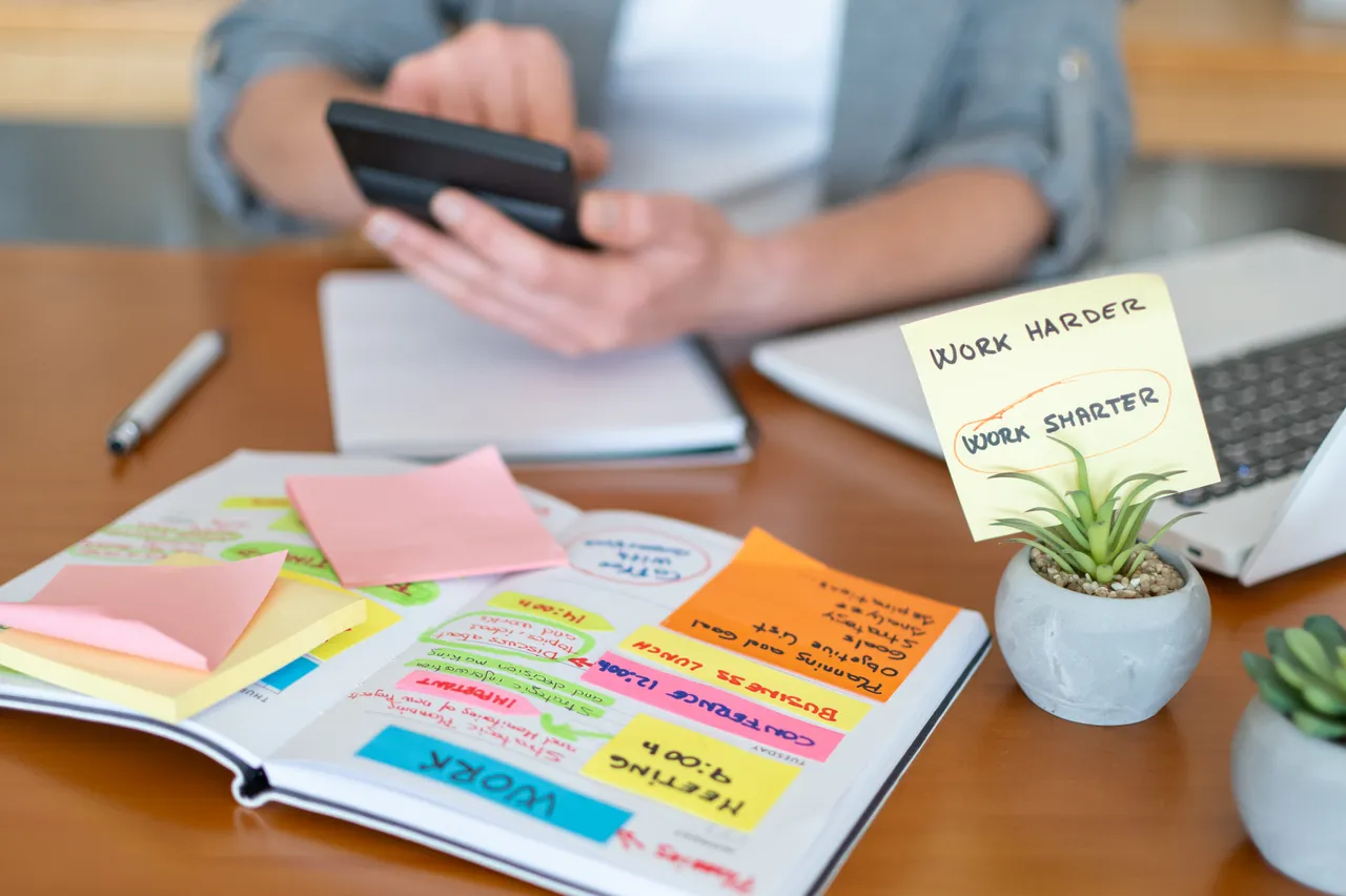 Cahier de notes manuscrites couvert de post-its à côté d'un smartphone