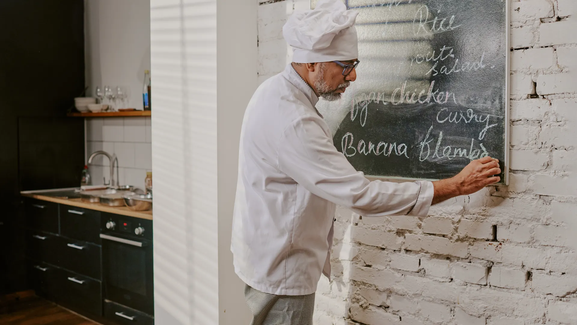 Chef écrivant le menu sur ardoise dans une cuisine de restaurant traditionnel